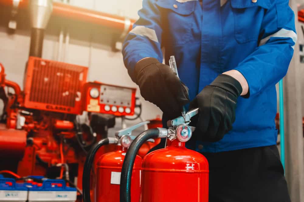 A technician carefully inspects and maintains fire extinguishers in a well-equipped workshop.