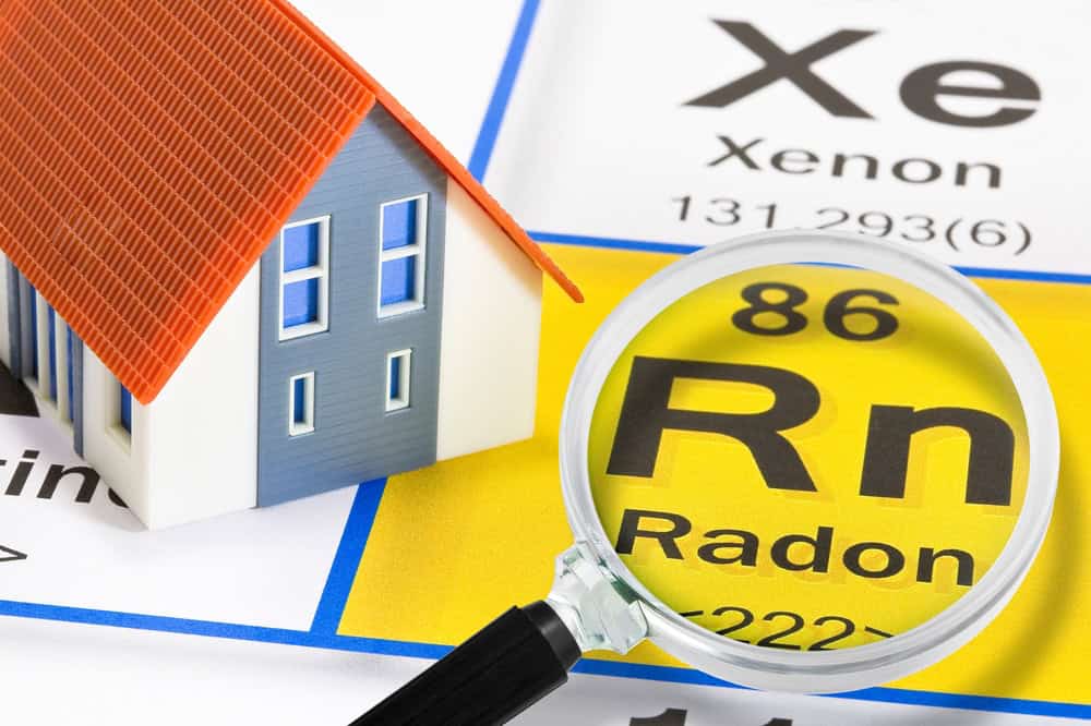 A magnifying glass reveals Radon (Rn) on the periodic table, highlighting the importance of radon detection in homes.