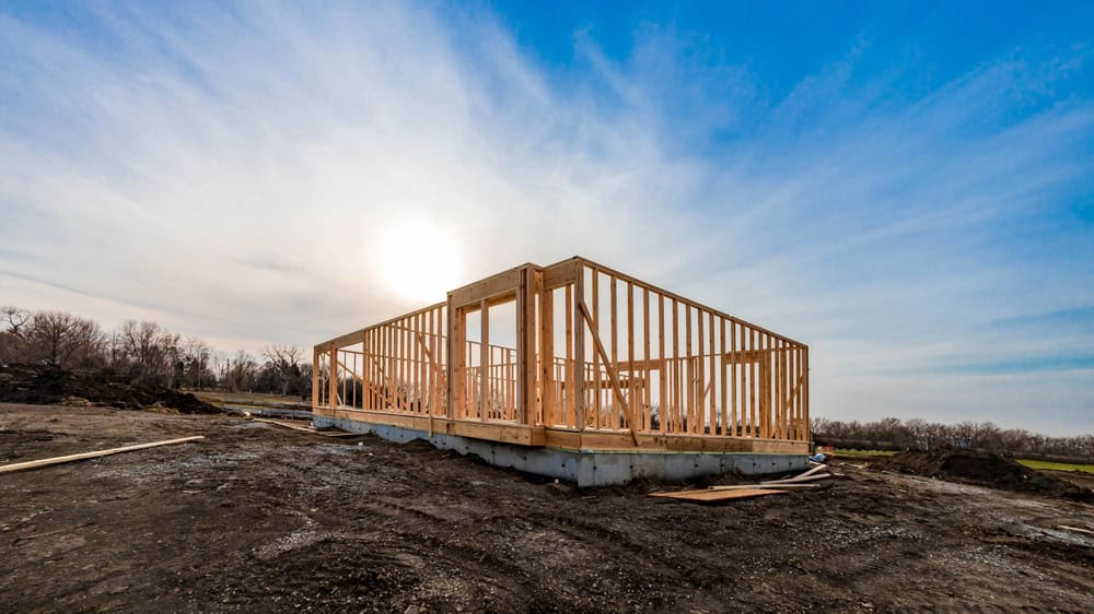A new home takes shape as wooden frames rise against a serene, sunlit sky.