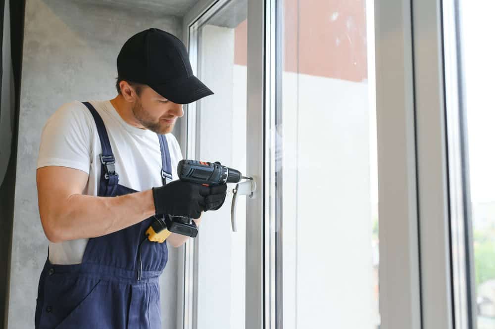 A handyman carefully installs a new window handle, ensuring a perfect fit.