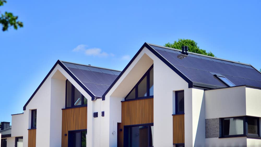 Modern eco-friendly homes with sleek solar panels under a bright blue sky.