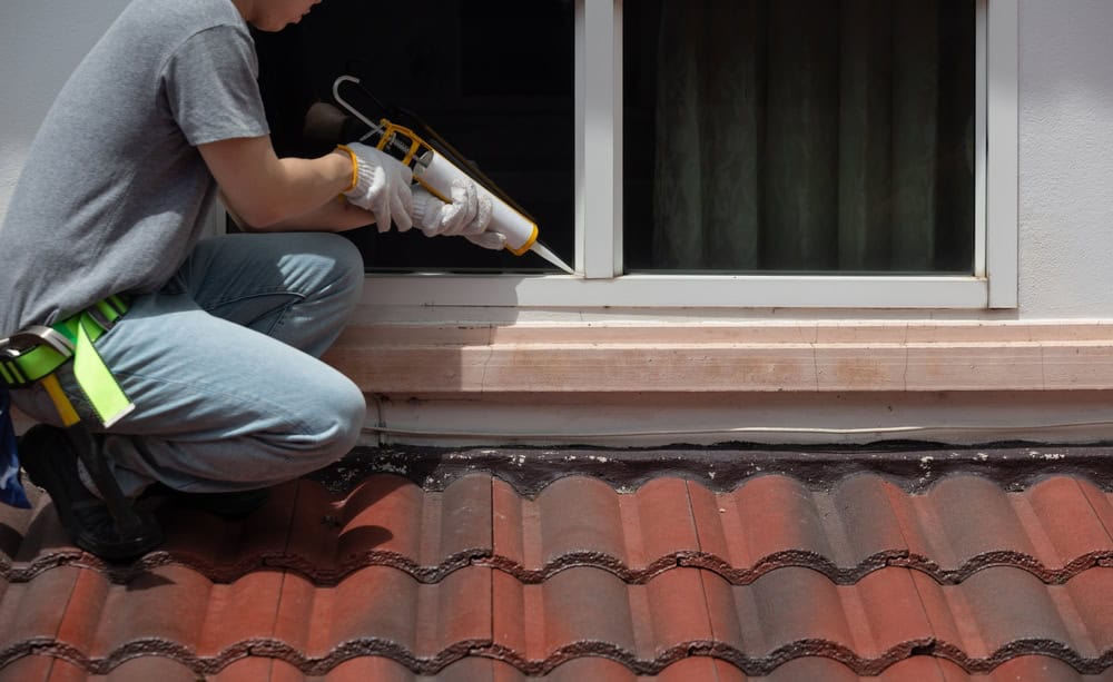 Sealing the deal! A worker carefully applies caulking to a window frame for a weatherproof finish.