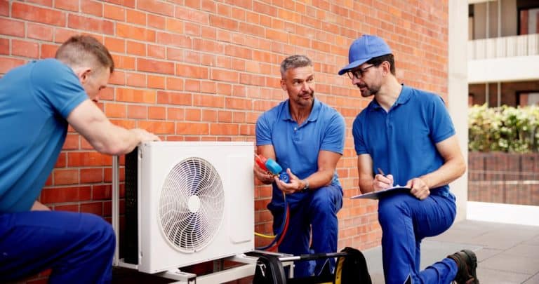 HVAC technicians collaborating on an air conditioning unit installation, ensuring efficiency and comfort.
