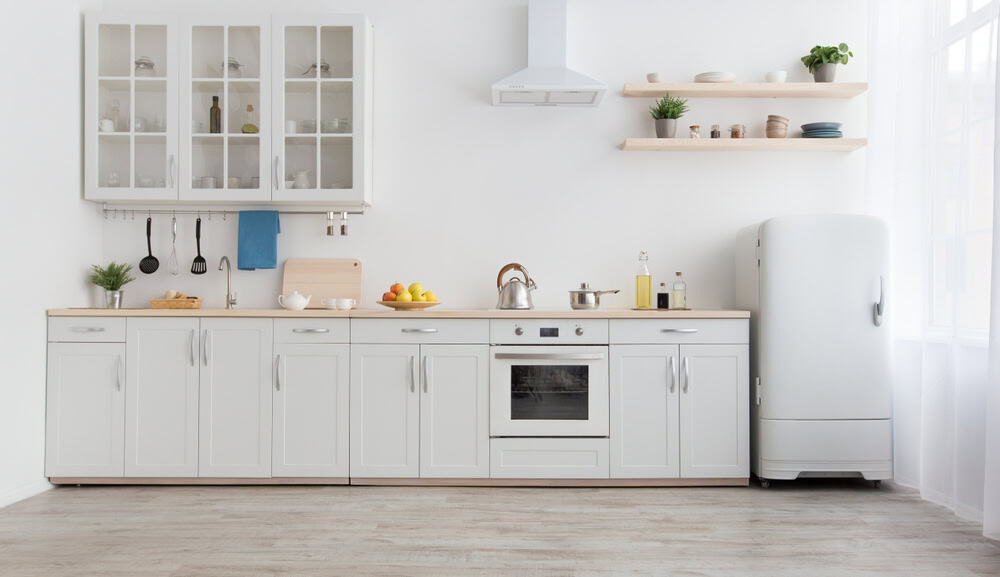 A bright, modern kitchen with white cabinets, wooden countertops, and a cozy window view.