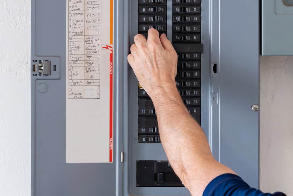 Flipping the switch: A close-up of a hand adjusting circuit breakers in an electrical panel.