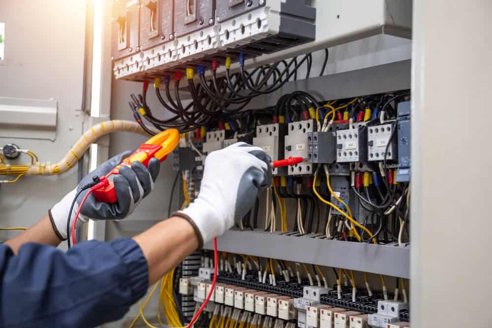 An electrician meticulously tests the voltage in an electrical panel, ensuring safety and functionality.
