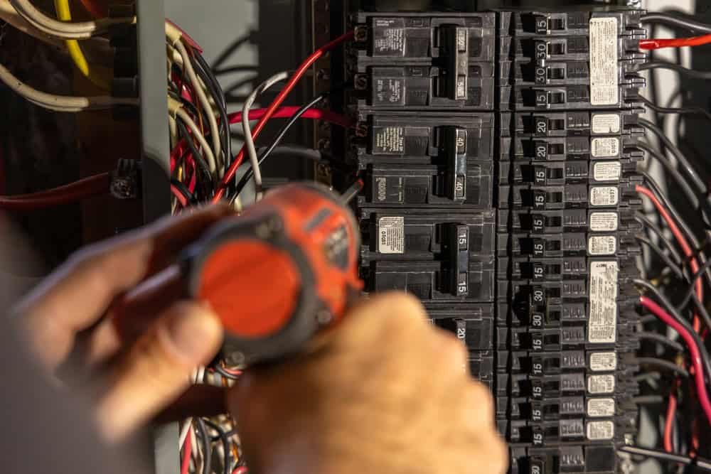 Precision at work—an electrician carefully inspects and adjusts a circuit breaker panel.