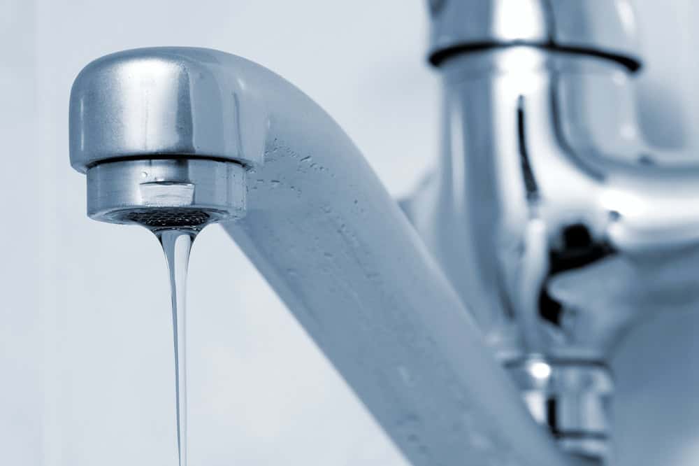 A single drop of water falls from a sleek, modern faucet.
