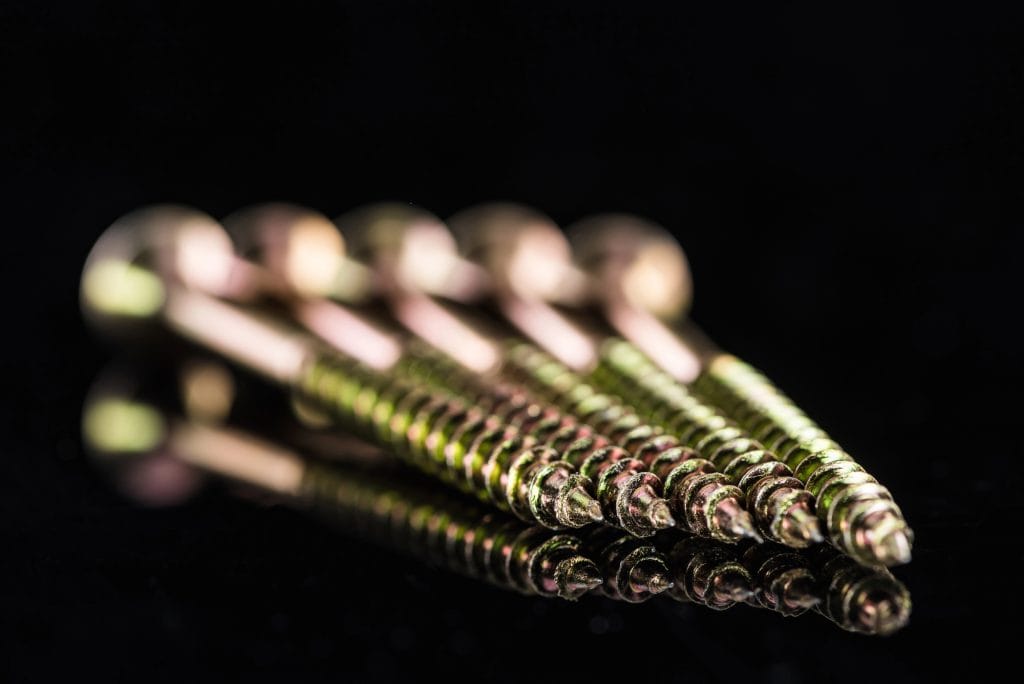 A close-up of precision-engineered screws against a sleek black background, showcasing their intricate threading and metallic sheen.