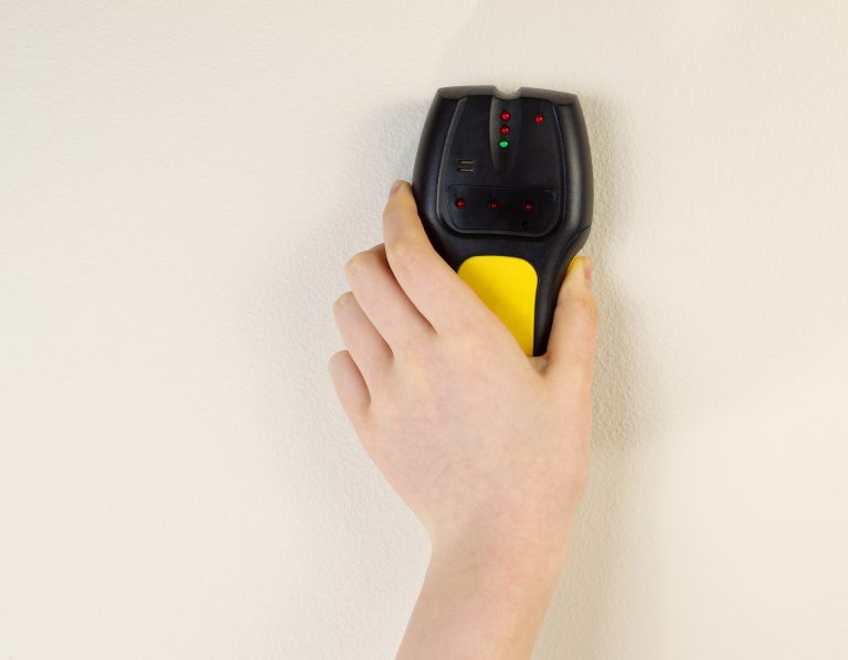 Finding the perfect spot! A stud finder in action.
