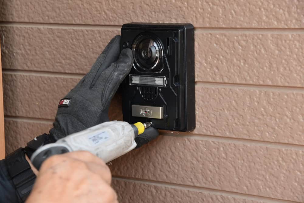 Installing a modern video doorbell on a textured wall.