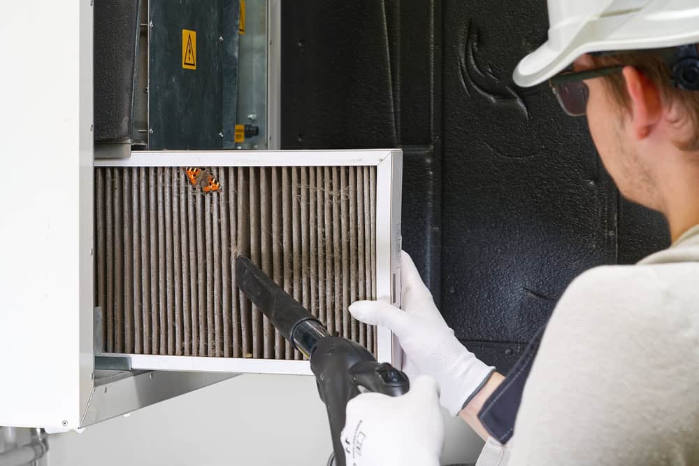 Technician cleaning an air filter with a vacuum cleaner to ensure optimal air quality.