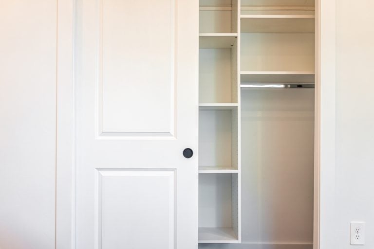 A sleek, modern closet with sliding doors and built-in shelving, offering ample storage space.