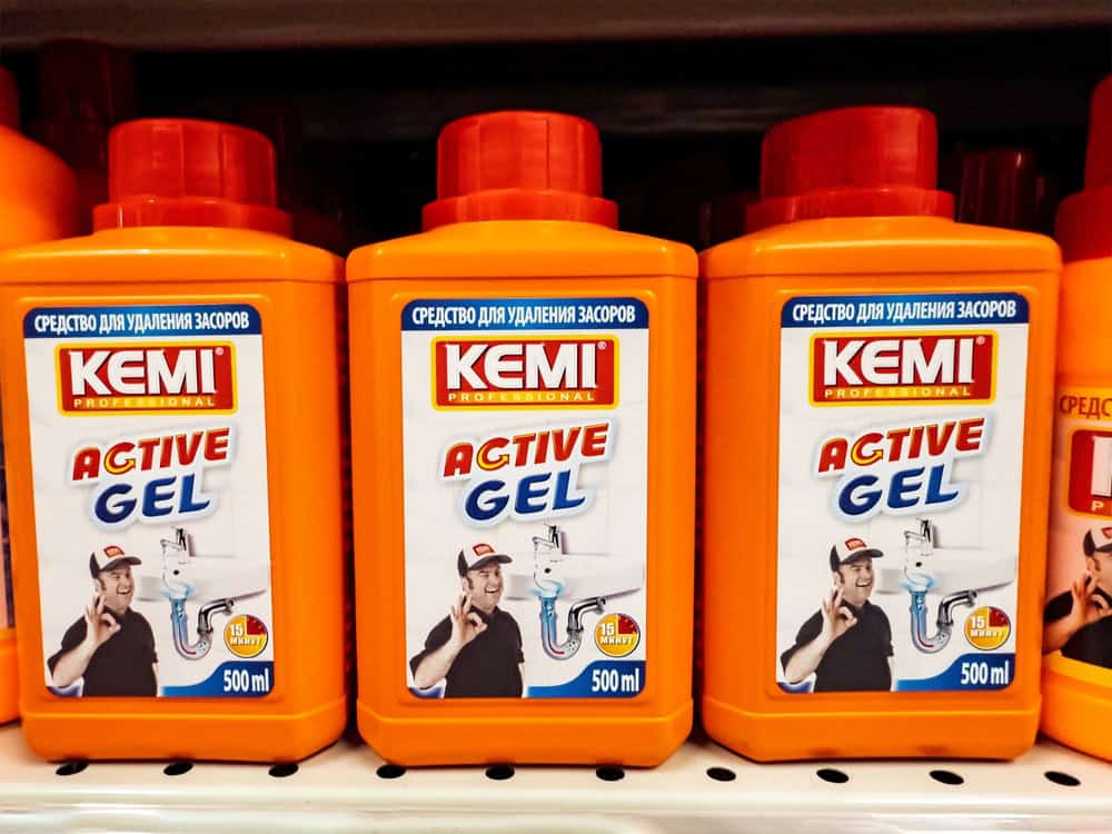 Bright orange bottles of KEMI Active Gel for rust removal line the store shelf, ready to tackle tough cleaning tasks.