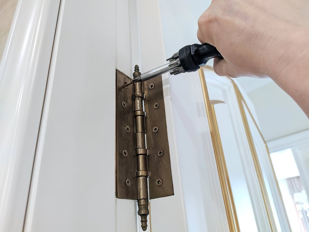 Tightening the screws on a vintage door hinge with precision.