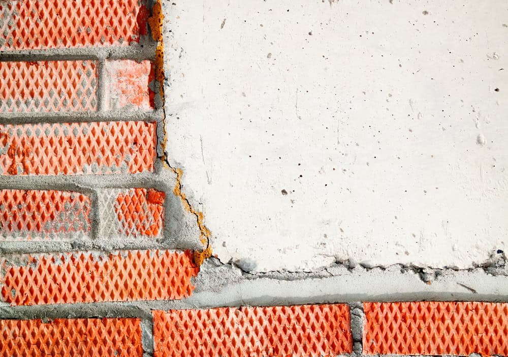 A weathered brick wall meets a stark white surface.