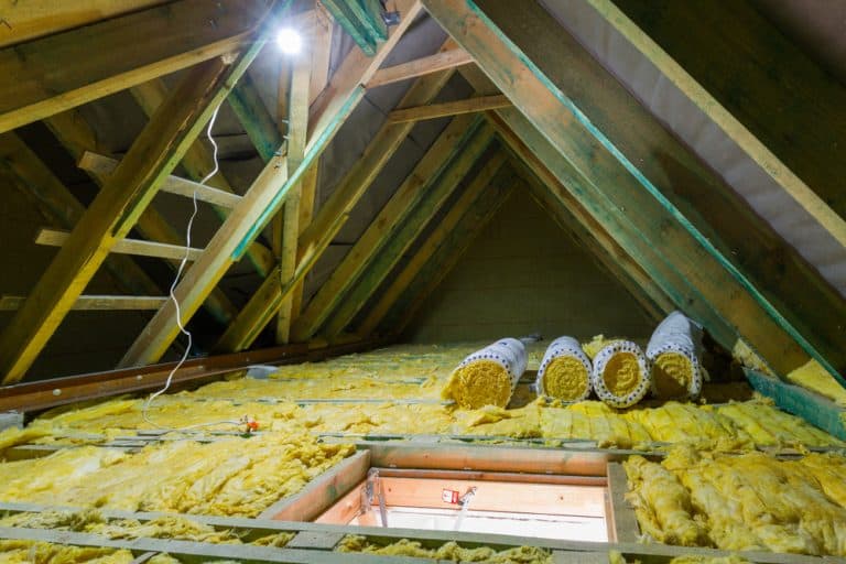 Cozy attic transformation in progress with freshly laid insulation and a skylight for natural light.
