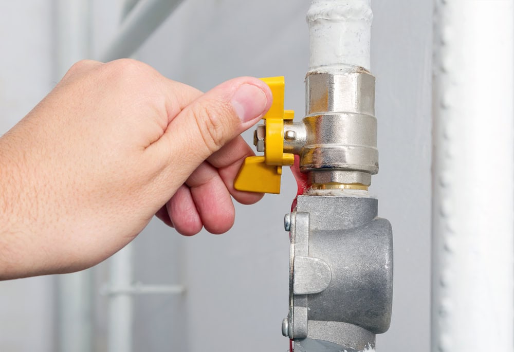 Turning the yellow gas valve shut for safety and maintenance.