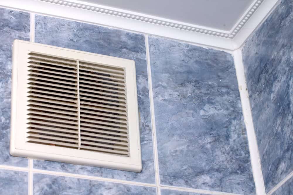A bathroom ventilation fan set in blue marbled tiles.