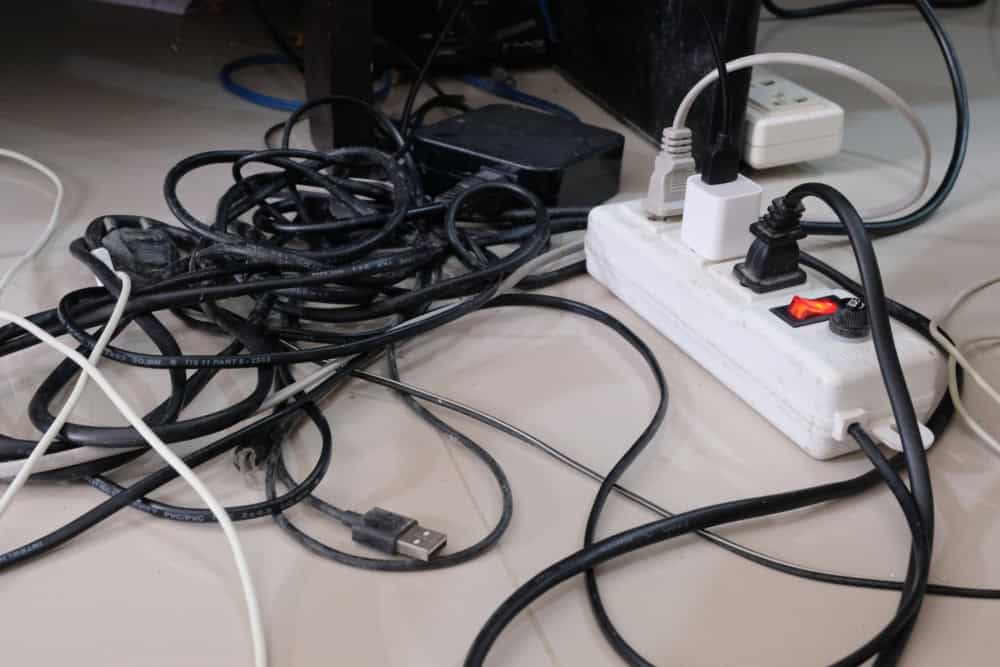 A chaotic tangle of cables and power strips under a desk.