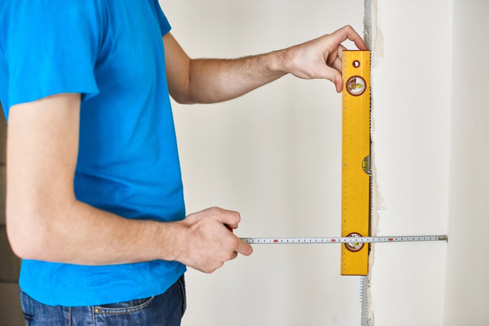 Measuring for precision with a spirit level and tape measure.