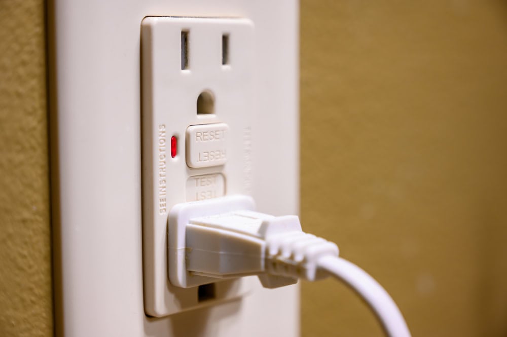 A close-up of a plug inserted into a GFCI electrical outlet.