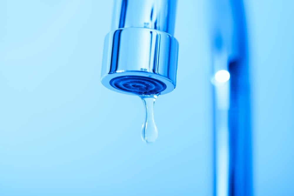 A single drop of water falls from a sleek, modern faucet.