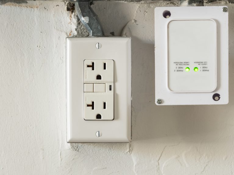 A GFCI electrical outlet and a dual-phase surge protector with green indicator lights.