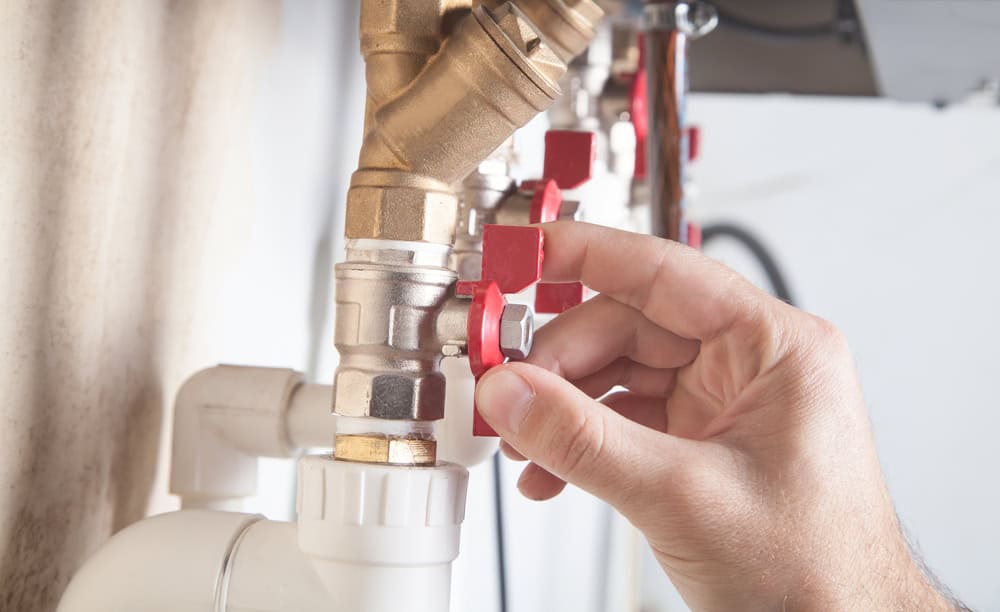 A technician adjusts a red valve on a modern plumbing manifold system.