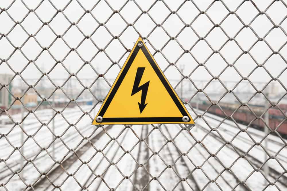 High voltage warning at a snowy railway crossing.
