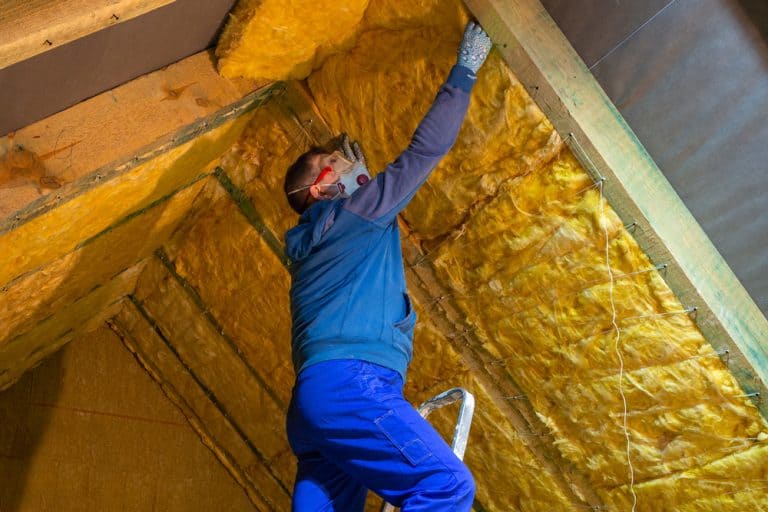 A worker installs insulation in an attic, ensuring energy efficiency and warmth.