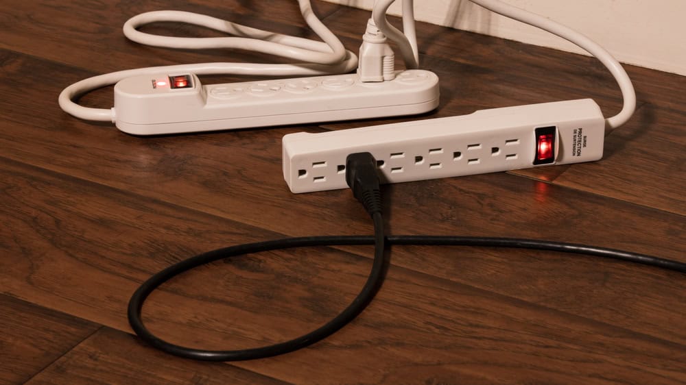Overloaded power strips on a hardwood floor.