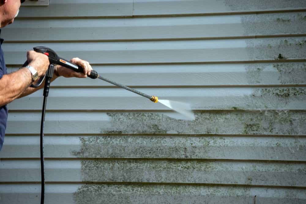 Power washing vinyl siding reveals dramatic before-and-after contrast as years of grime and mildew disappear beneath the high-pressure spray.