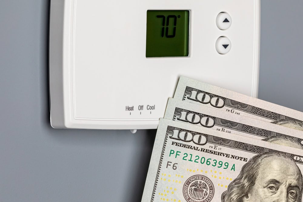 "Money vs. Comfort: Thermostat set to 70° with $100 bills, illustrating the cost-benefit balance of home temperature control"