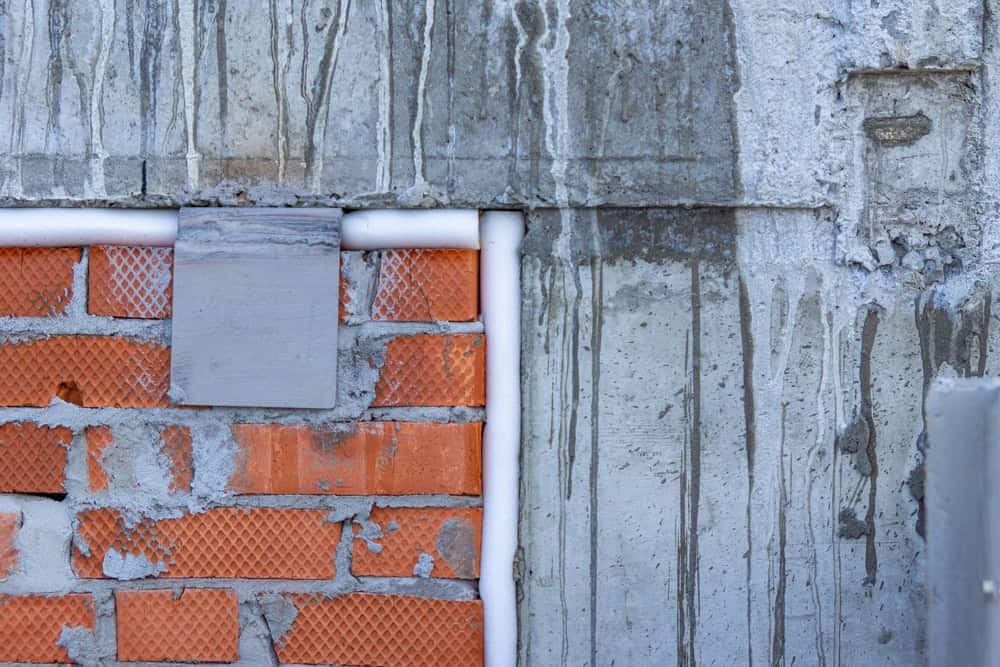 A weathered wall where old brick meets new concrete.