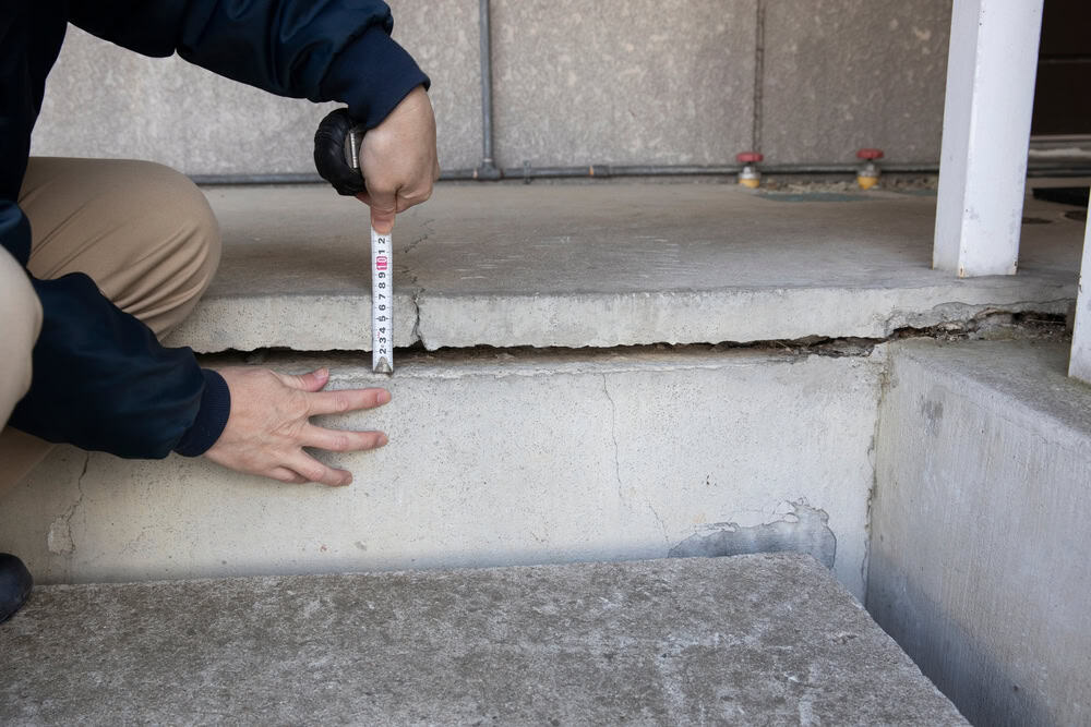 Assessing structural damage: Measuring a significant crack in concrete steps.