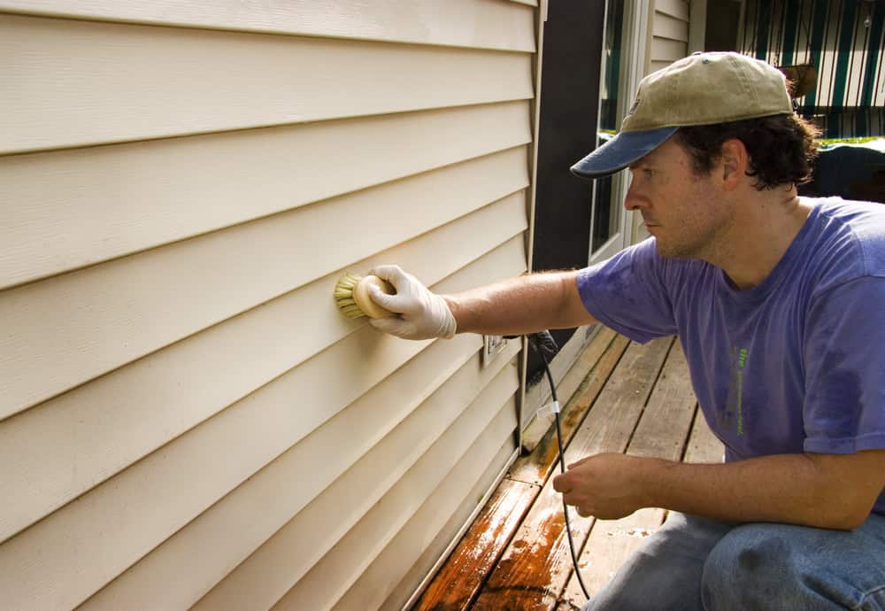 Cleaning the exterior of a house with a brush.