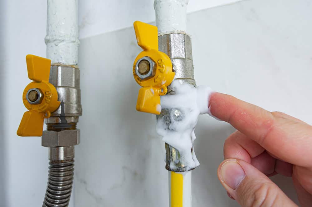 Gas shutoff valve leaking soap suds during a DIY plumbing leak test