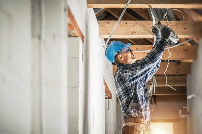 Electrician at work installing wiring in a new residential construction site, ensuring safe and efficient power systems.