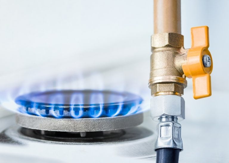 Blue flame from a gas burner next to a brass shut-off valve.