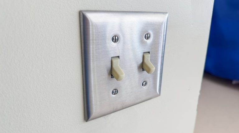 A modern, sleek double light switch with a metallic finish