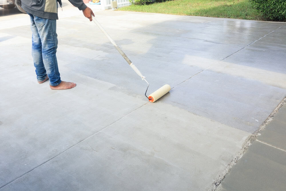 Applying a fresh coat of sealant to a concrete driveway for a smooth, protective finish.