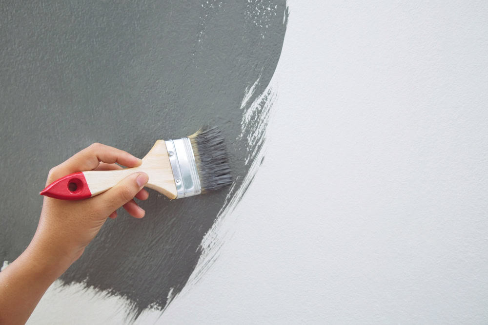 Hand painting a wall gray.