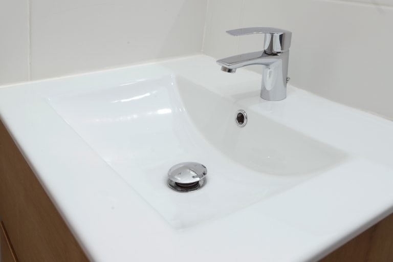 Sleek and modern white ceramic sink with a chrome single-lever faucet in a minimalist bathroom setting.
