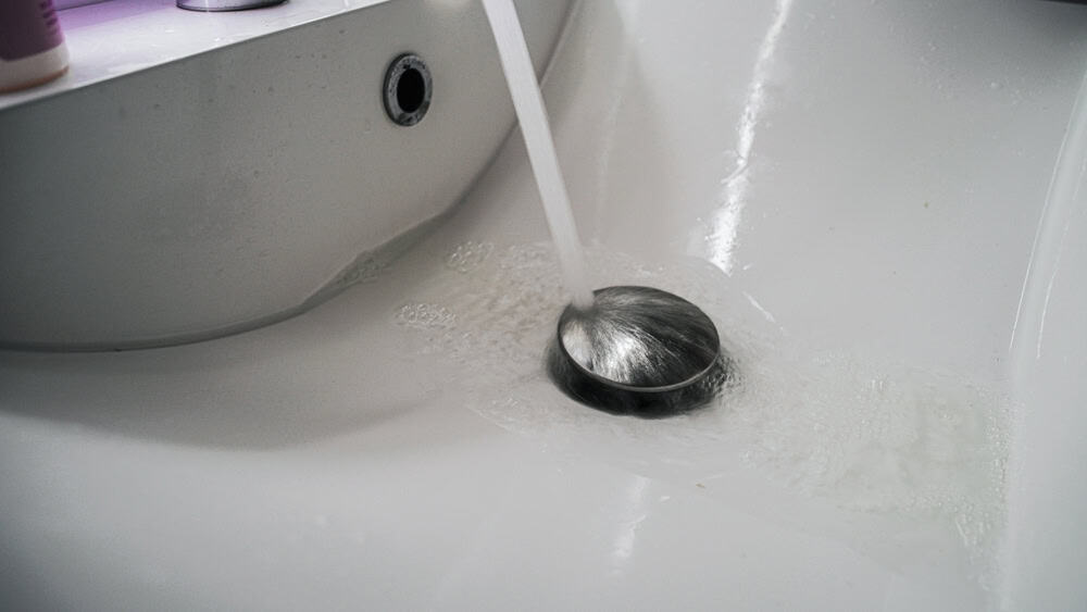 Water flows into a modern bathroom sink.