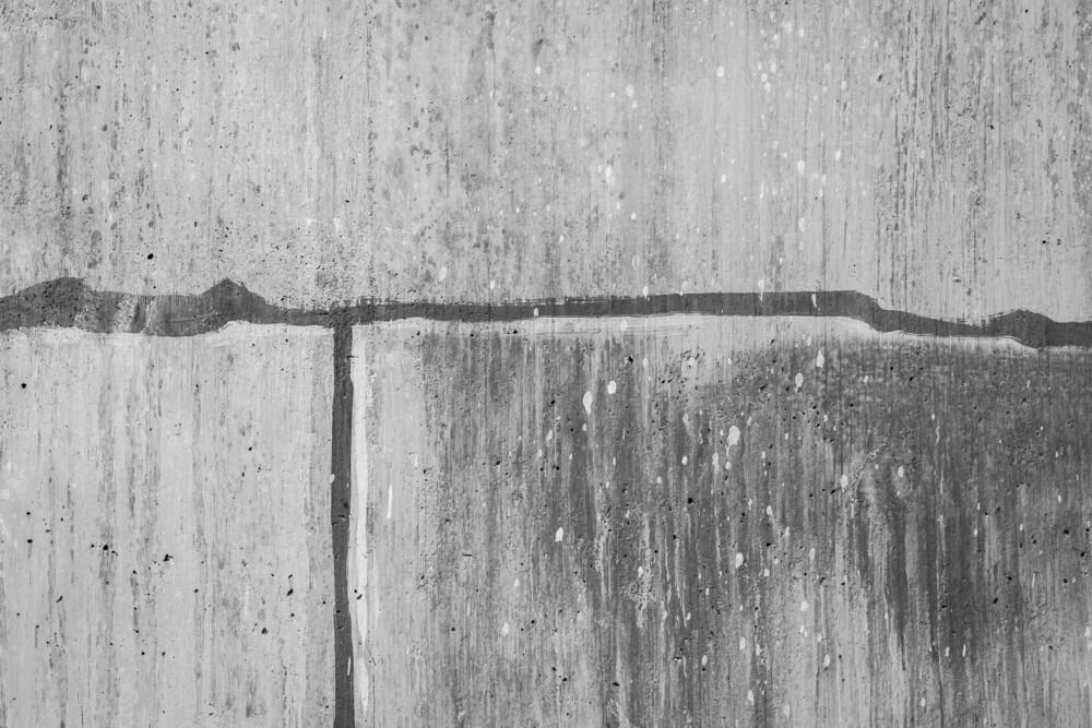 Weathered concrete wall with streaks and stains.