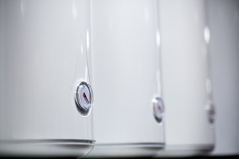 Row of modern white water heaters with temperature gauges, ready to deliver hot water efficiently.