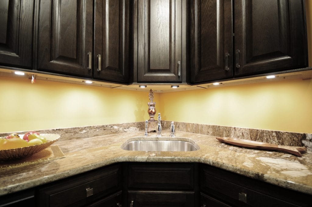 Elegant kitchen corner with rich dark wood cabinets, warm lighting, and a luxurious marble countertop.
