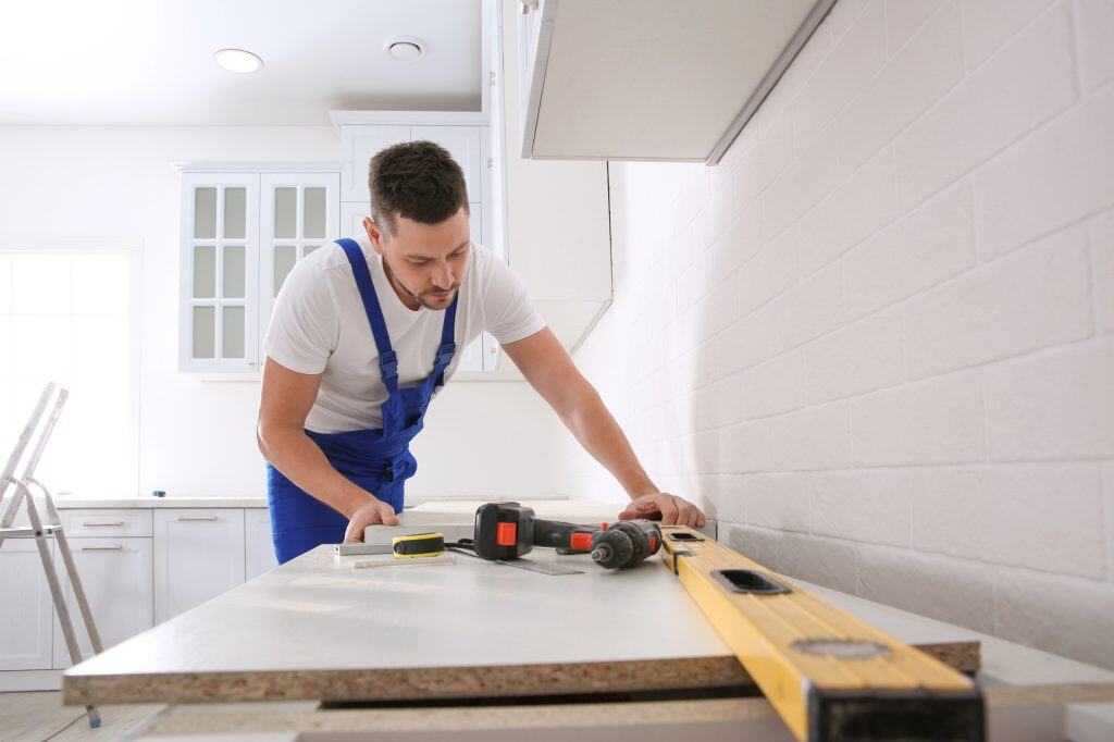 A carpenter meticulously installs a new kitchen countertop, ensuring precision with his tools.