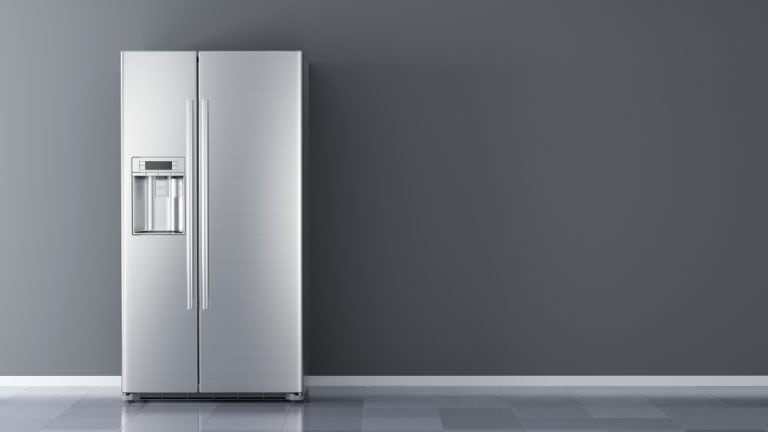 Sleek stainless steel refrigerator against a minimalist dark grey wall